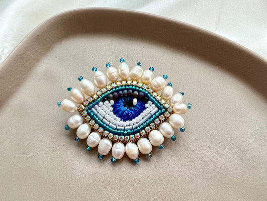 Beaded eye-shaped accessory on a beige surface