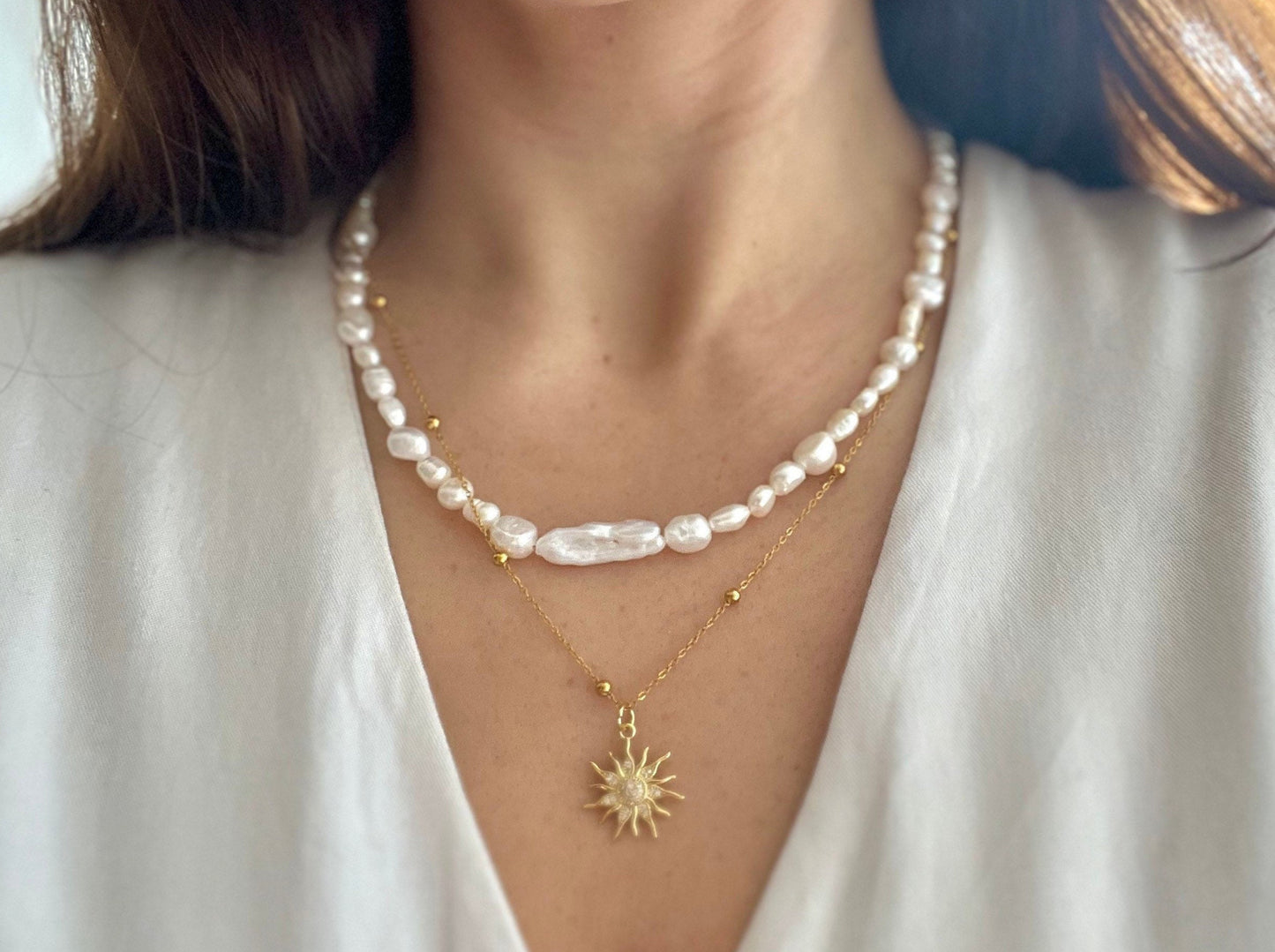 Pearl necklace with a sun pendant on a white shirt