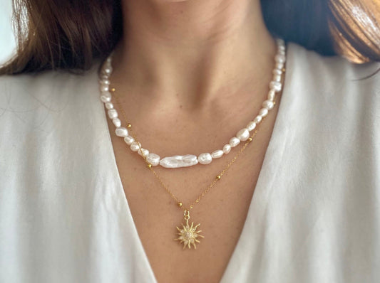 Pearl necklace with a sun pendant on a white shirt