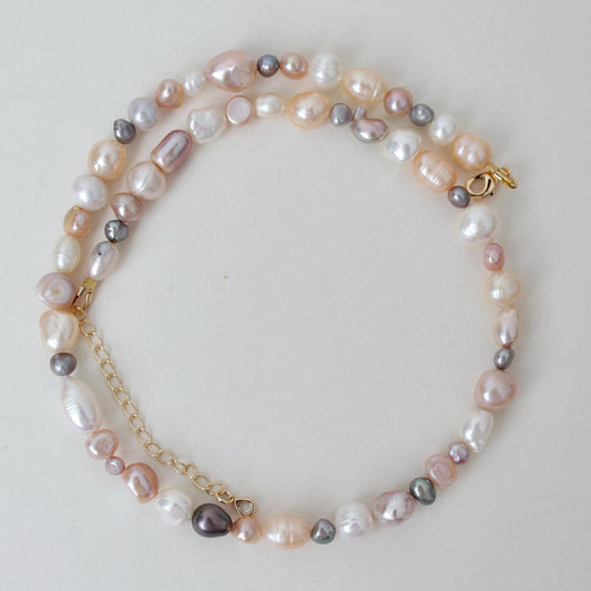 Pearl necklace with gold chain on a light background